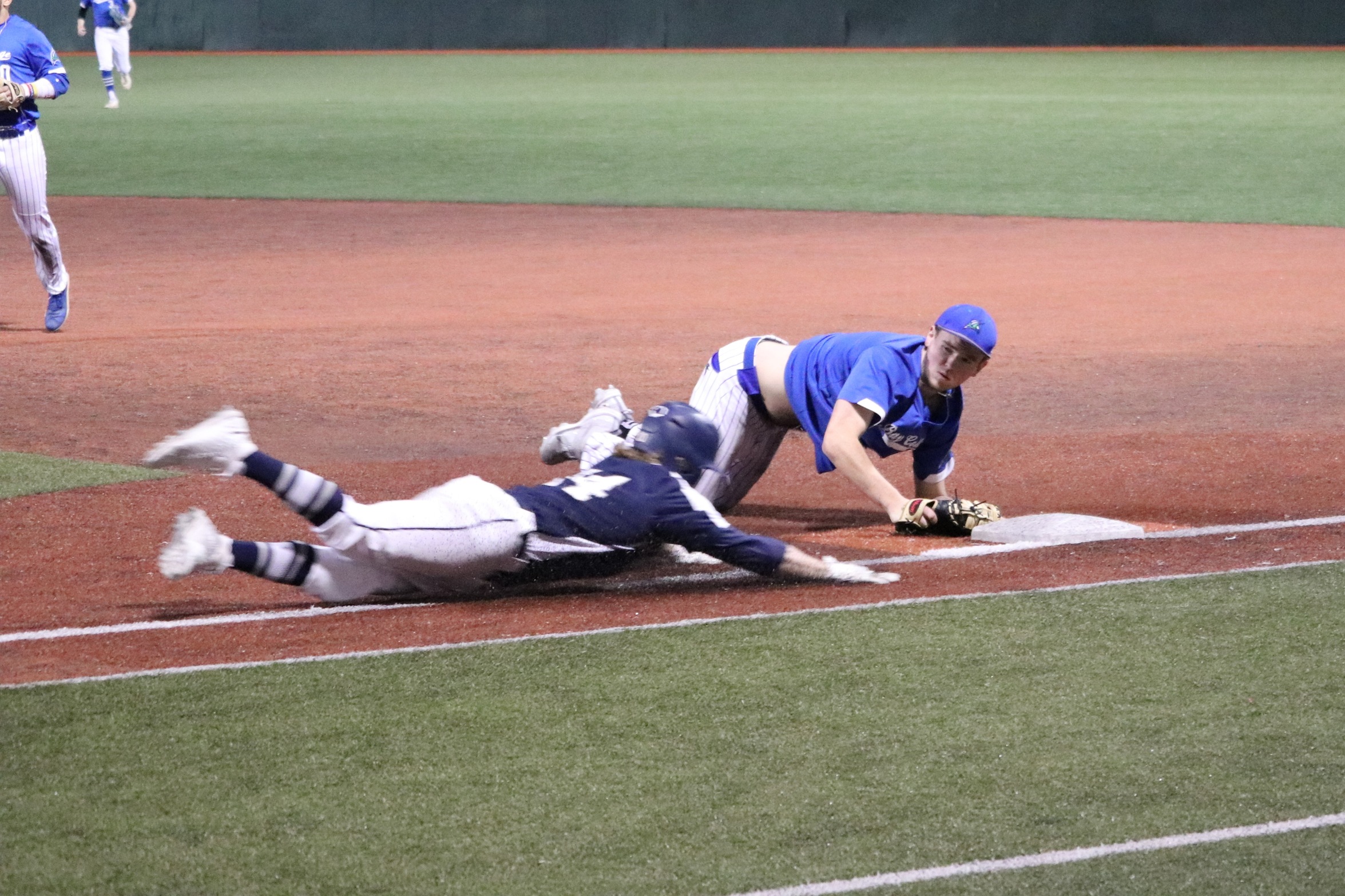 Jared Crow dives back to the bag, just beating a sliding runner to first for the out