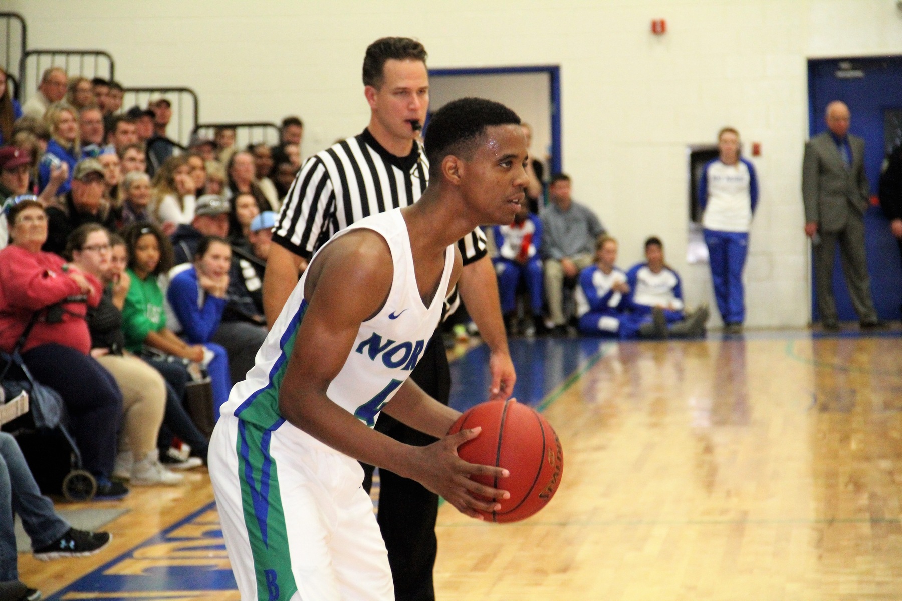 Alfonzo Fields holds the ball in front of an full gym of spectators