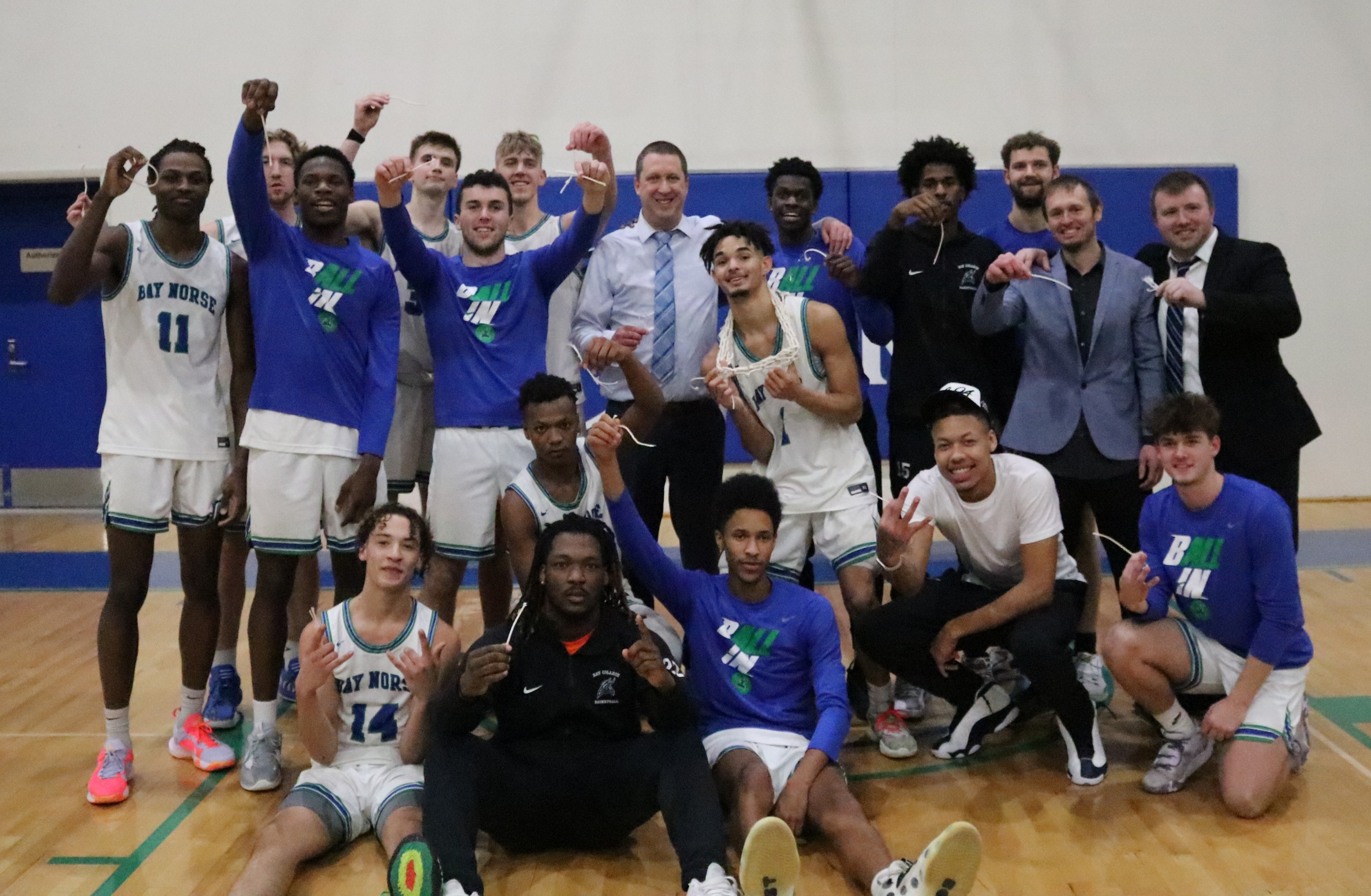 The Bay College Men's Basketball Team pose together after cutting down the net