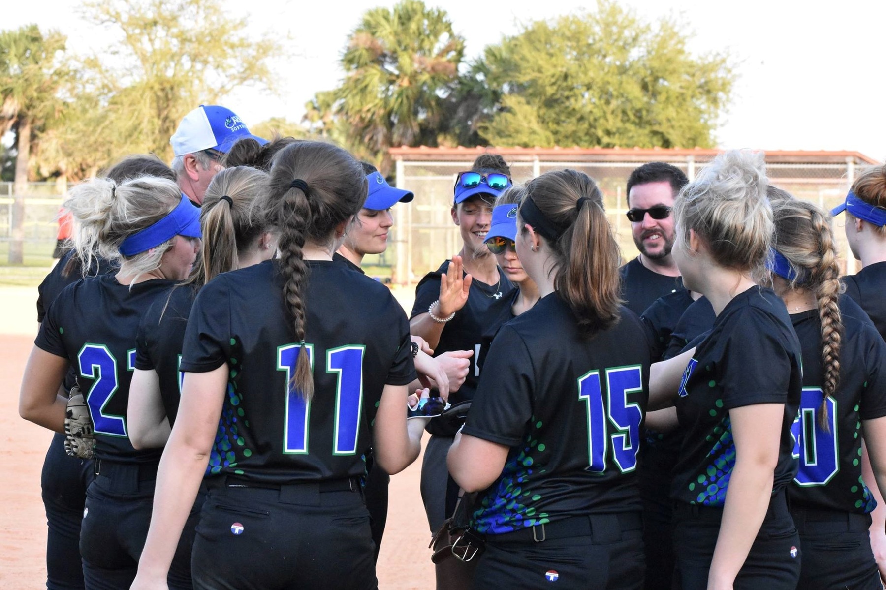 Norse softball players and coaches gathered in a huddle
