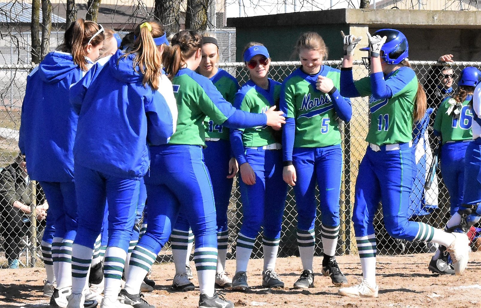 Kaitlyn Hardwick crosses the plate after hitting a homerun, her teammates surround the plate