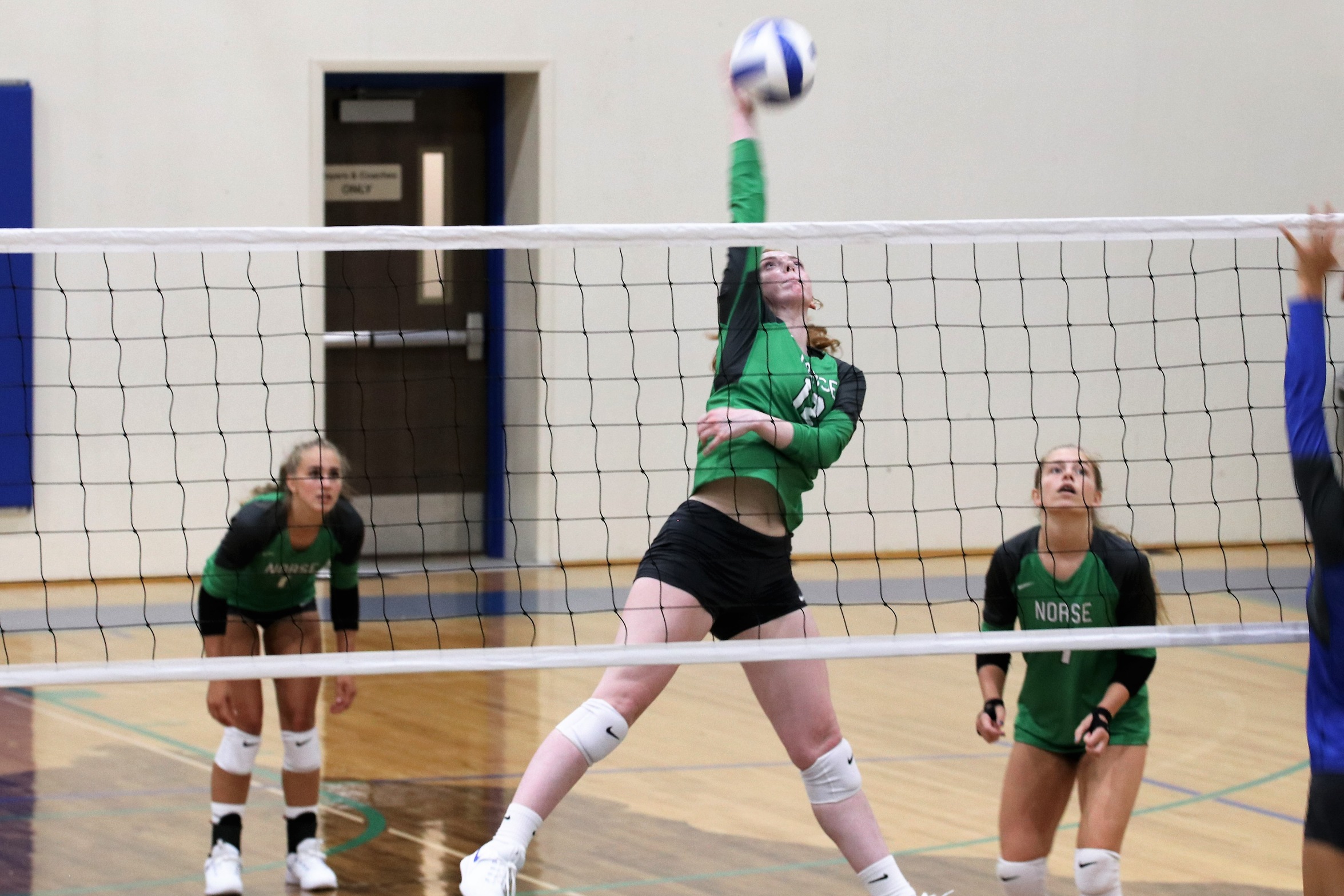 Kylee Tadisch extends in the air for a kill, her teammates looking on