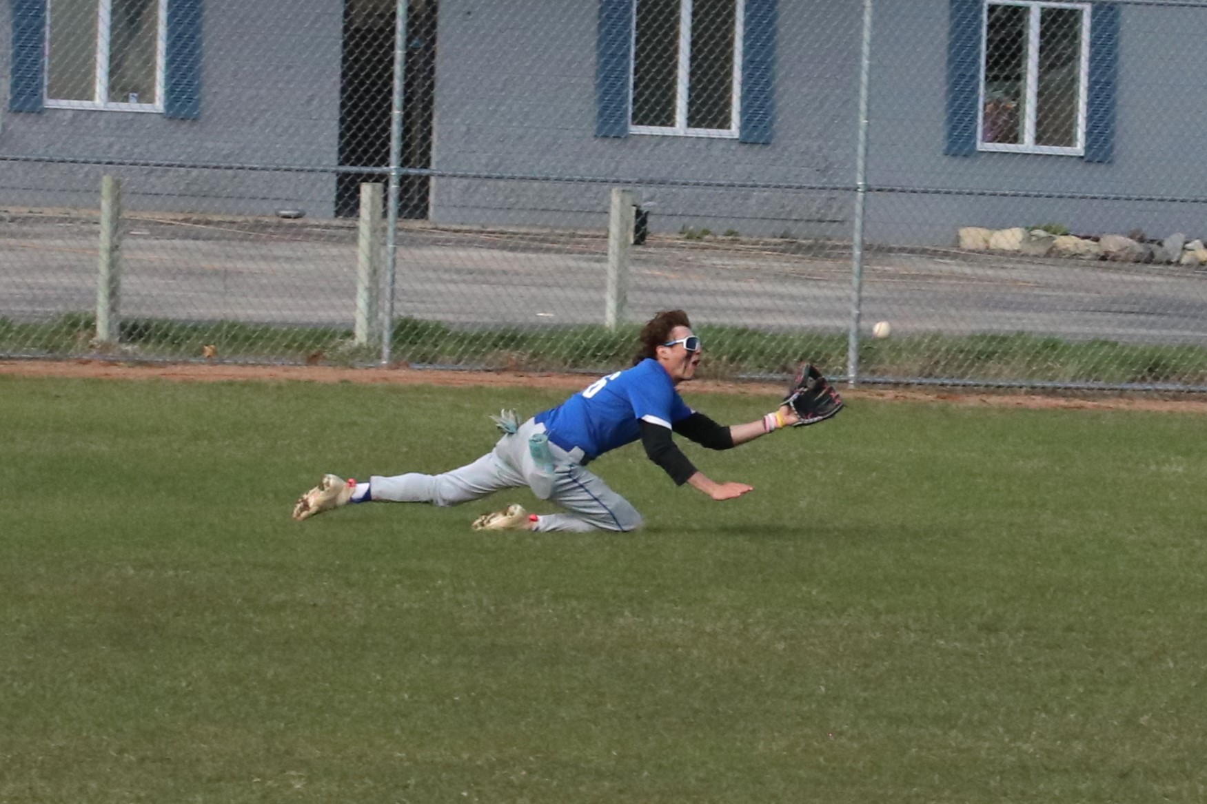 Jace Cota sliding in the outfield, he is reaching for a ball he is about to catch