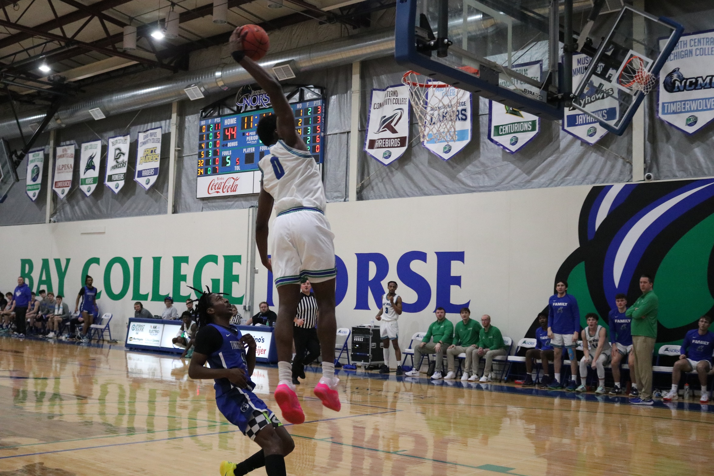 Baril Mawo in mid-air, on his way for a one-handed dunk as a defender looks on
